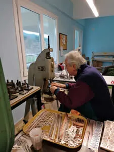 How We Make Copper Jewelry: Artisan cutting jewelry with special precision tools at the workshop bench.